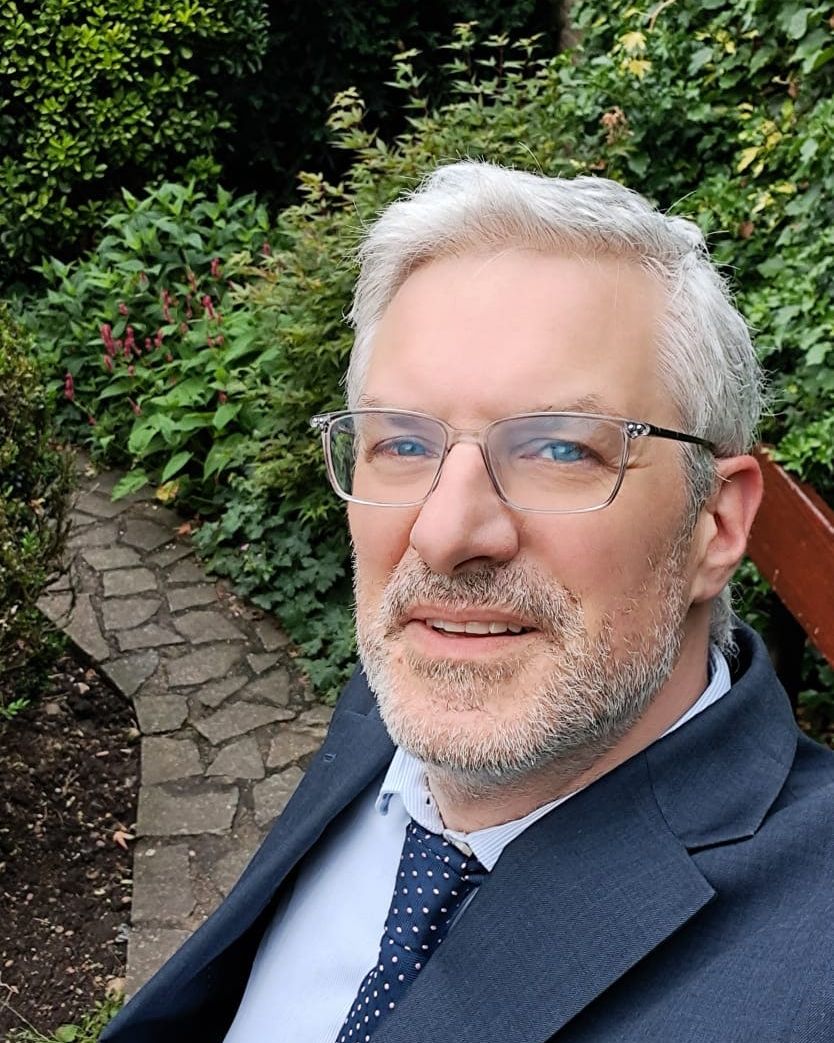 Ben Morris, founder of Techsperience, smiling in a suit and tie in a leafy garden