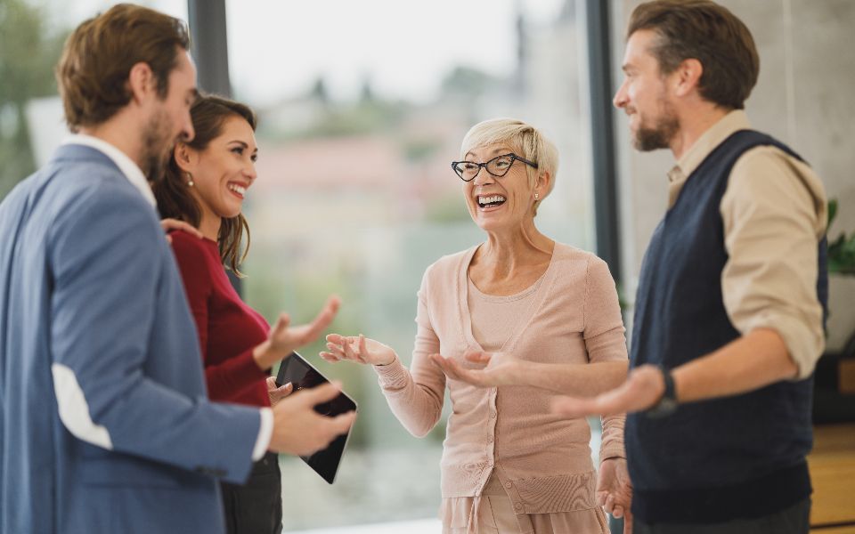 Four people in conversation, standing together in a bright office