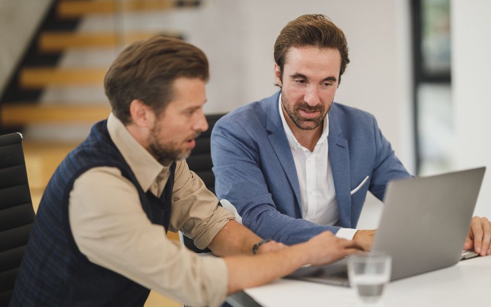 Two colleagues working through something together at a laptop